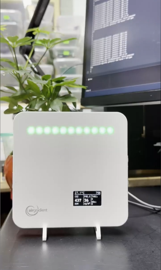 AirGradient air-quality monitor on a desk showing CO2, PM2.5 and temperature